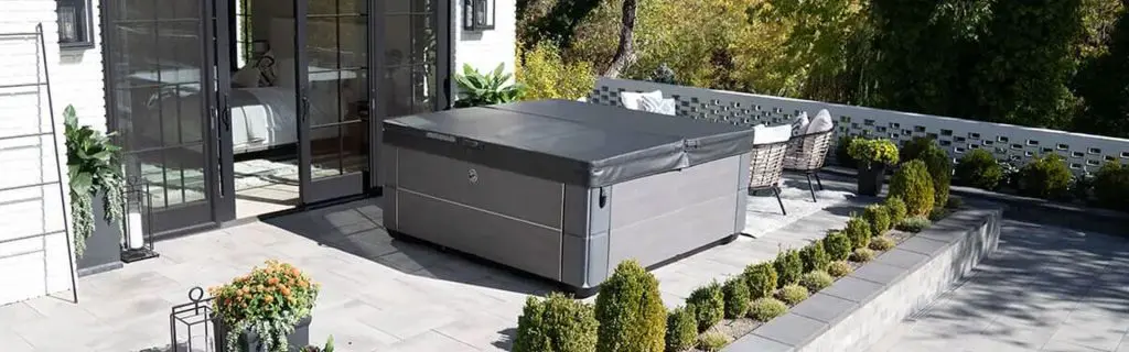 Hot tub on a stylish patio surrounded by greenery and modern outdoor furniture, showcasing backyard design ideas for outdoor living spaces.