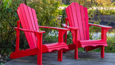 Red Adirondack chairs positioned on a wooden deck surrounded by greenery, highlighting outdoor lawn furniture designed for comfort and style in backyard settings.
